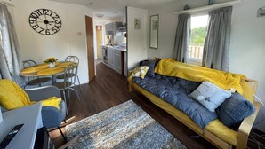 Ein gemütliches Wohnzimmer mit einer Couch, einem Esstisch und einer Küche im Hintergrund.