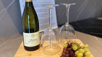 Une bouteille de vin, deux verres à vin et une grappe de raisins sur une planche en bois.