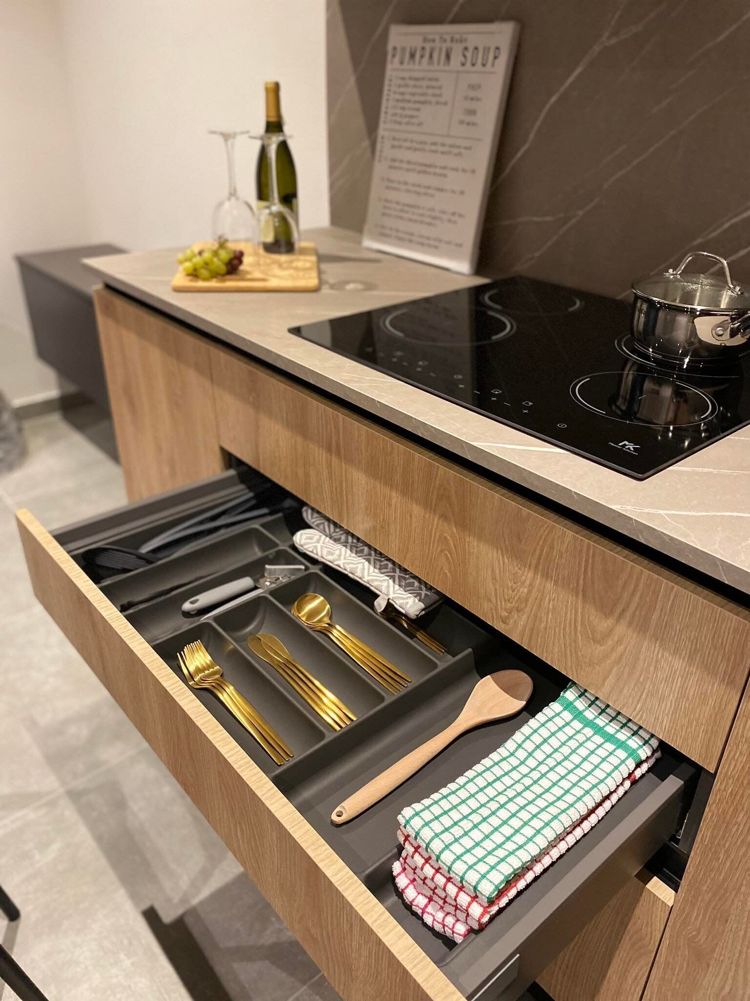 Une cuisine équipée d’une cuisinière intégrée, une bouteille de vin et un panneau affichant le menu.