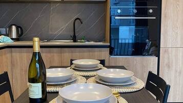 Une cuisine moderne avec des meubles en bois, un four encastré et une table à manger dressée avec des assiettes et une bouteille de vin.