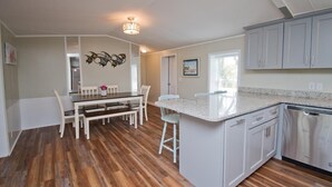 A spacious kitchen with wooden flooring, white cabinetry, and a central island. - Sandy Oaks, Soundview House in Salter Path, NC! (Salter Path)