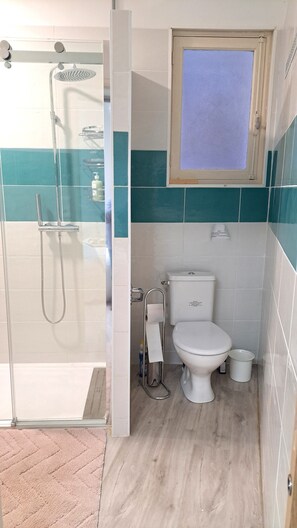 Een douche, handdoeken, zeep, toiletpapier