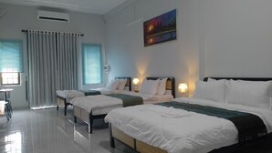 Una habitación de hotel con tres camas, una mesa de comedor y un cuadro en la pared.