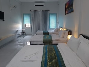 Habitación de hotel con dos camas, una mesita con sillas, un televisor y un cuadro en la pared.