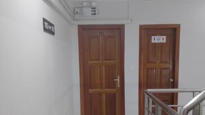 Un pasillo con dos puertas de madera, una con la etiqueta 101 y otra con el símbolo de un inodoro.