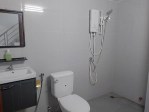 Un baño con inodoro, lavamanos, espejo y cabina de ducha.