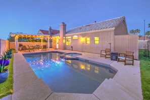 Un giardino con piscina, mobili da patio e una zona relax coperta.