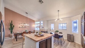 Cozinha moderna com ilha central, área de refeições com cadeiras e uma janela grande que proporciona luz natural.