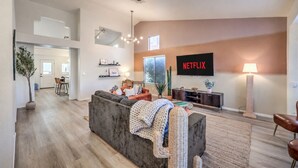 Uma sala de estar moderna com um sofá cinzento, uma TV de tela plana e uma luminária.