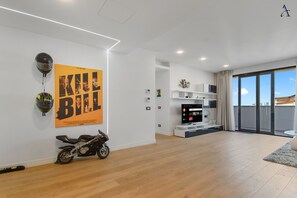 Un salon moderne avec une moto, un téléviseur et une grande affiche accrochée au mur.
