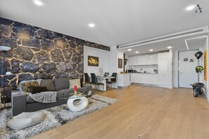 Un salon moderne avec un mur d’accent en pierre, un coin repas et une cuisine.