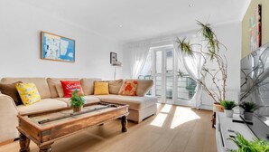 A modern living room with a sofa set, a coffee table, and potted plants. - Golden Sunset House Free Parking | By My Getaways (Brighton)