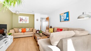 A modern living room with two sofas, a coffee table, and a TV. - Golden Sunset House Free Parking | By My Getaways (Brighton)