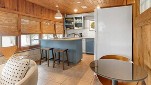 A kitchen with wooden ceiling, a bar area, and a dining table. - Waterlily Serenity / 2 Bedroom / Creekside (Wimberley)