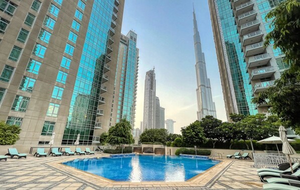 A swimming pool surrounded by high-rise buildings, including the Burj Khalifa.