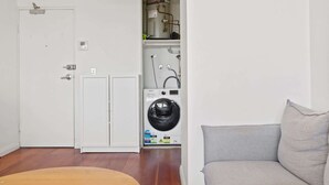 A compact laundry room with a washing machine, a dryer, and a water heater. - Prime Location 2-Bed Apartment with Parking (Centennial Park)