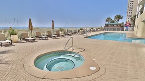 Zona de piscina con sillones de descanso y jacuzzi, con vista a una playa.