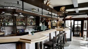 Un espace bar doté d’un comptoir incurvé, de plusieurs tabourets et d’étagères remplies de bouteilles et de verres.