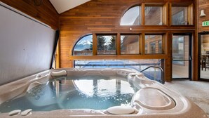 Een hottub in een ruimte met houten wanden en grote ramen.