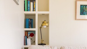 Un salon avec une bibliothèque, une lampe et un canapé agrémenté de coussins jaunes.