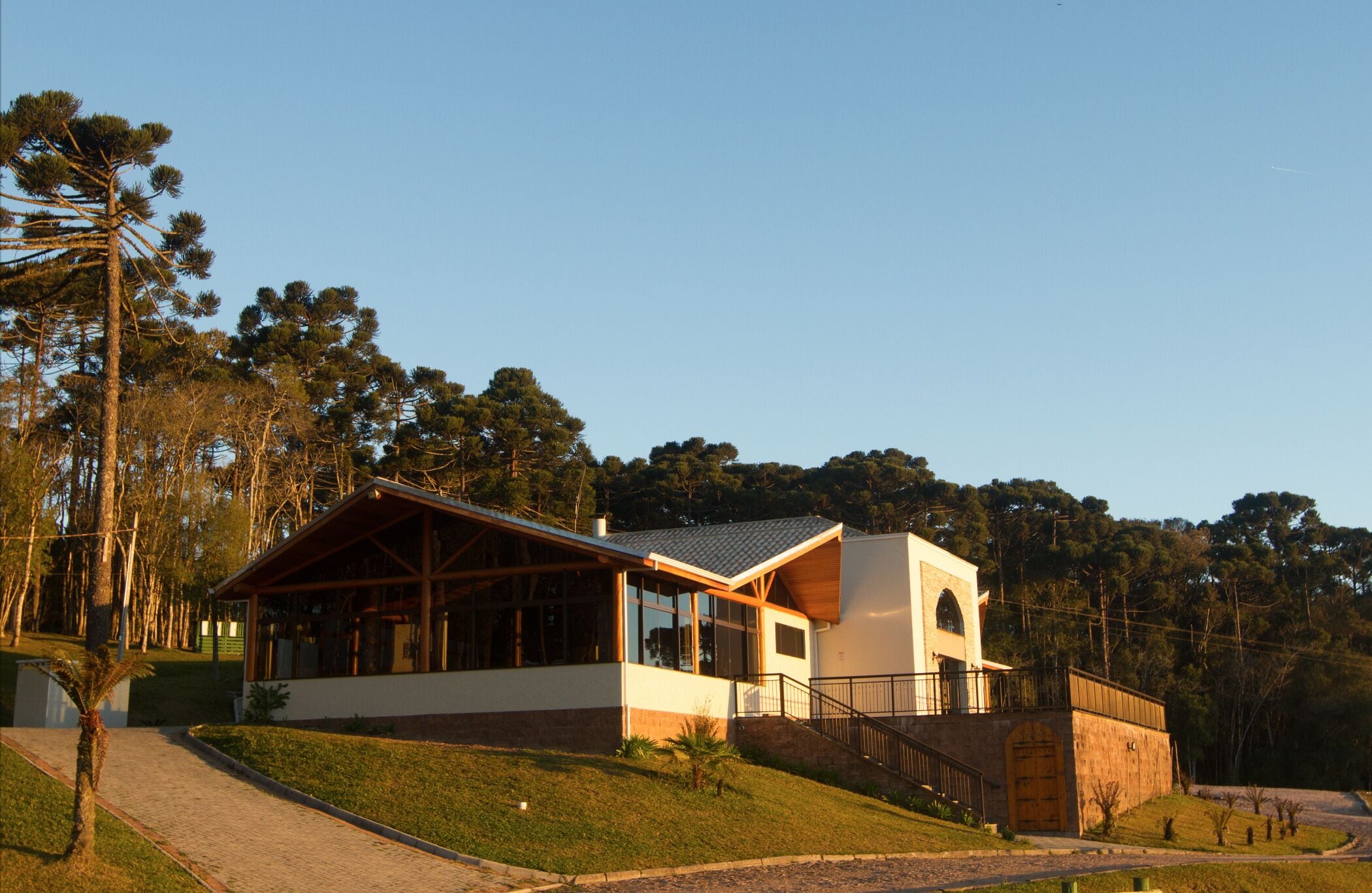 A modern building with a large glass facade, a wooden deck, and a stone base.