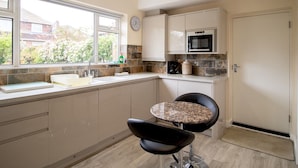 A modern kitchen with a built-in microwave, a sink, and a window overlooking a garden. - Welcoming Family Home - Pass the Keys (North Shields)