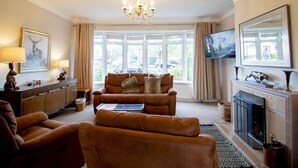 A living room with a sofa, a fireplace, a television, and a chandelier. - Welcoming Family Home - Pass the Keys (North Shields)