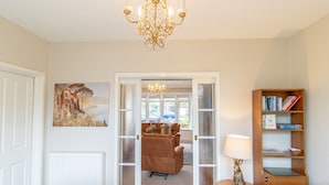 A bedroom with a bed, a chandelier, a painting, a sofa, a table, and a bookshelf. - Welcoming Family Home - Pass the Keys (North Shields)