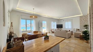 Una sala de estar moderna con una mesa de comedor de madera, un sofá y un televisor.