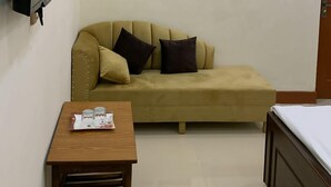 A small, well-lit room with a sofa, a table with glasses, and a bed. - Hotel Almarkaz (Islamabad)