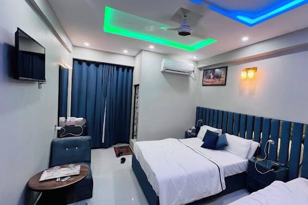 Una habitación de hotel con dos camas, televisión, aire acondicionado y un cuadro en la pared.