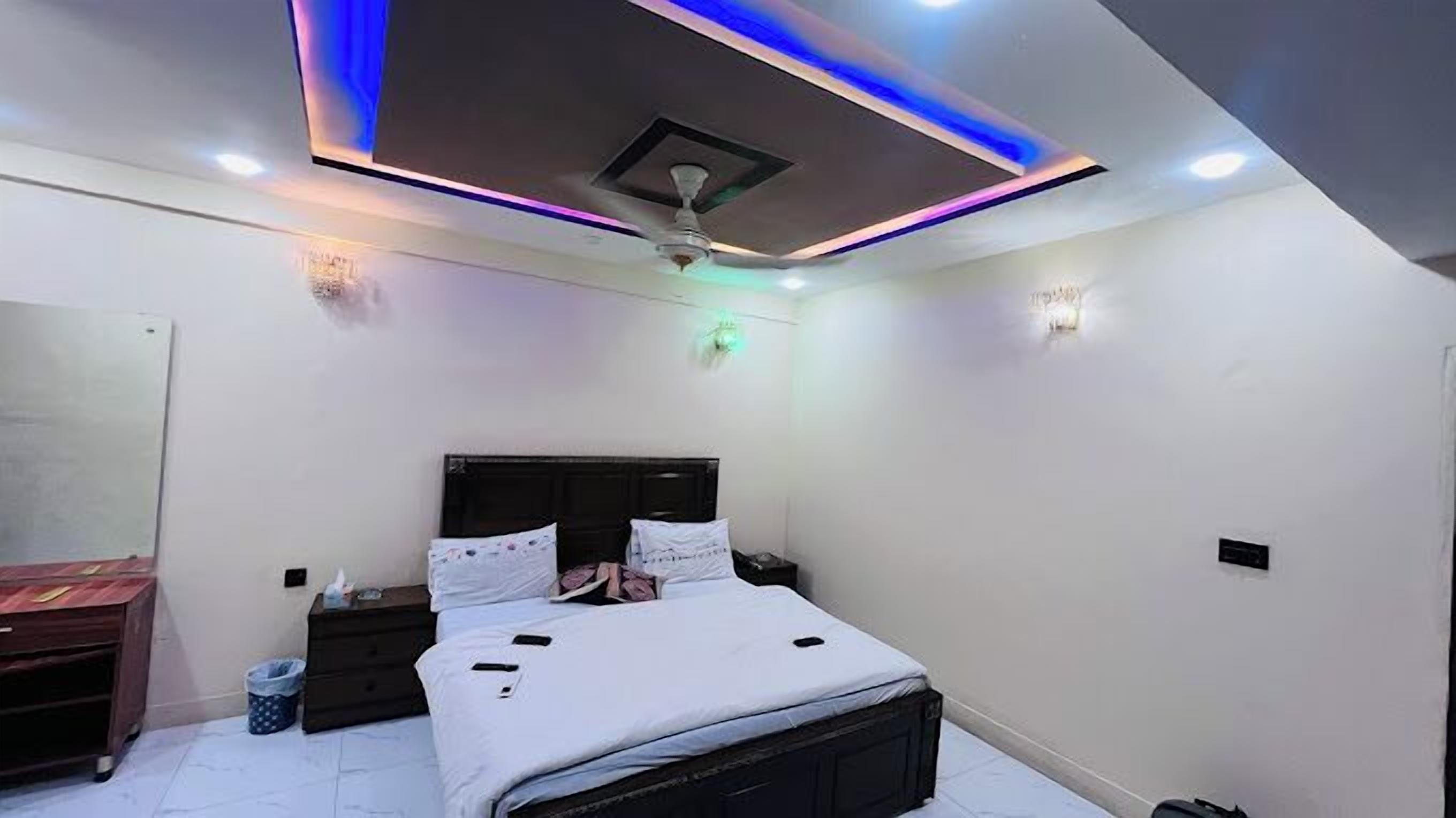 A bedroom with a bed, bedside tables, a ceiling fan, and recessed lighting.
