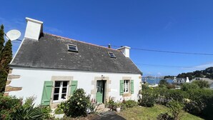 Una casa blanca con contraventanas verdes, una chimenea y una antena parabólica.
