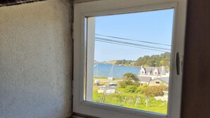 Una ventana con vistas a la costa, que incluye una masa de agua, barcos y edificios.