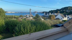 Vista costera desde una ventana con vista a un puerto deportivo con barcos, un puente y casas.