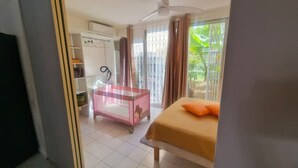 Quarto com uma cama, uma escrivaninha, uma cadeira e uma janela com cortinas.