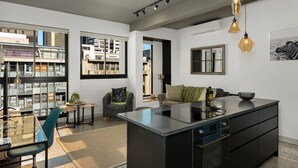 A modern kitchen with a central island, a dining area with a glass table, and a view of the city through large windows. - Modern Living In Heart of CBD Wifi Pool (Cape Town)
