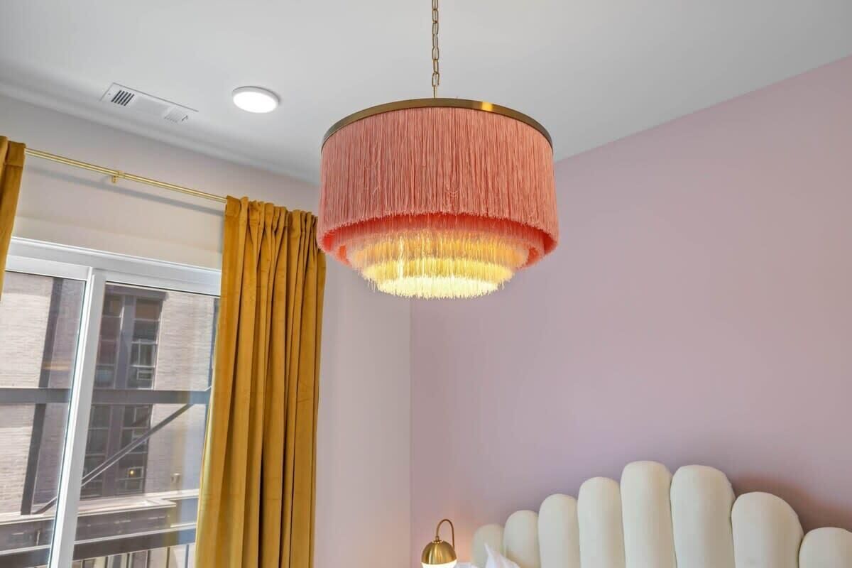 Serene and Sophisticated: Delight in a modern escape within this beautifully designed bedroom, adorned with soft pink walls and a chic white headboard, creating an ambiance of tranquility and elegance.
