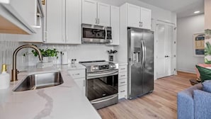 Una cocina moderna con armarios blancos, electrodomésticos de acero inoxidable y encimera de mármol.