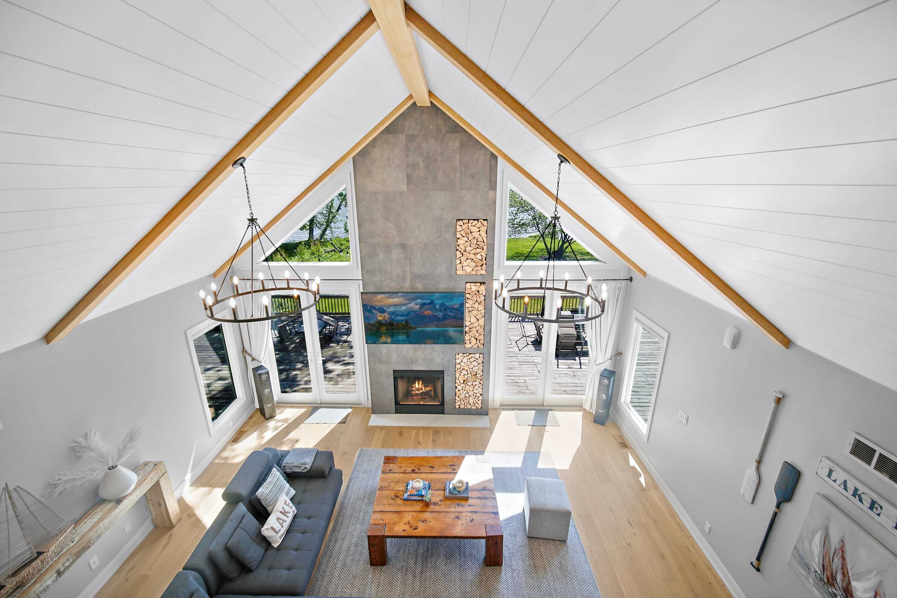 Un loft spacieux avec de hauts plafonds, une cheminée, une grande fenêtre donnant sur un lac et un coin salon confortable.