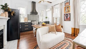 A modern kitchen with a black refrigerator, white cabinetry, and a patterned backsplash. There is a dining area with a white sofa and a wooden table. - Solar Flair (Atlanta)