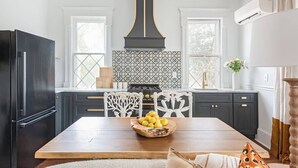 A modern kitchen with dark cabinetry, a central island, and a patterned backsplash. - Solar Flair (Atlanta)