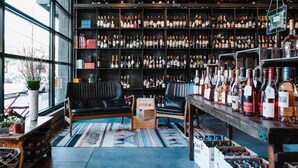 A bar with a large wine selection, a black leather couch, and a view through large windows. - Solar Flair (Atlanta)