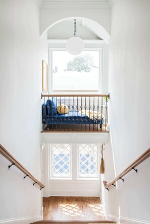 A staircase leading to a balcony with a blue sofa and a hanging light fixture.