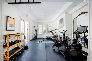 A gym with exercise equipment, a rack of dumbbells, and a large mirror.