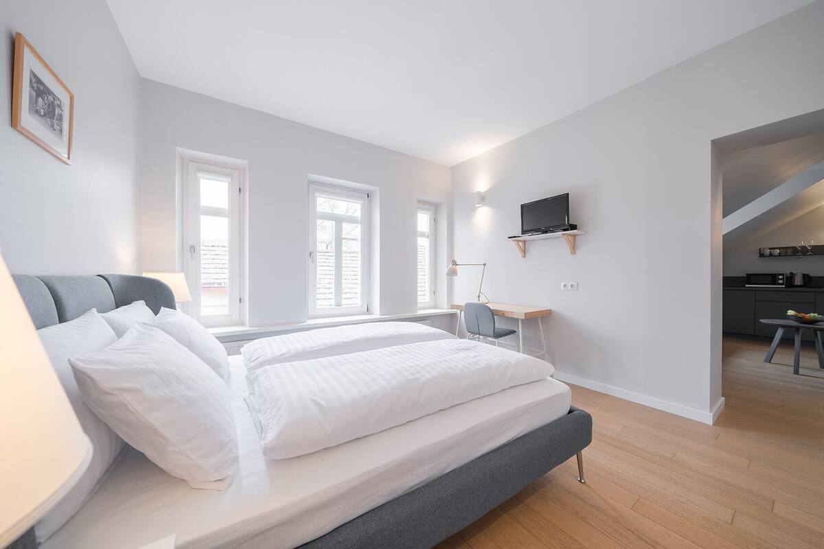 A modern bedroom with a bed, bedside table, and a TV mounted on the wall.