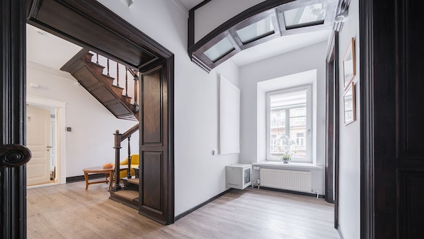 A spacious hallway with a wooden staircase, a radiator, and a window with a view of the street. - Lollo Self Check-in Residence - Lollo Luxury (Vilnius)