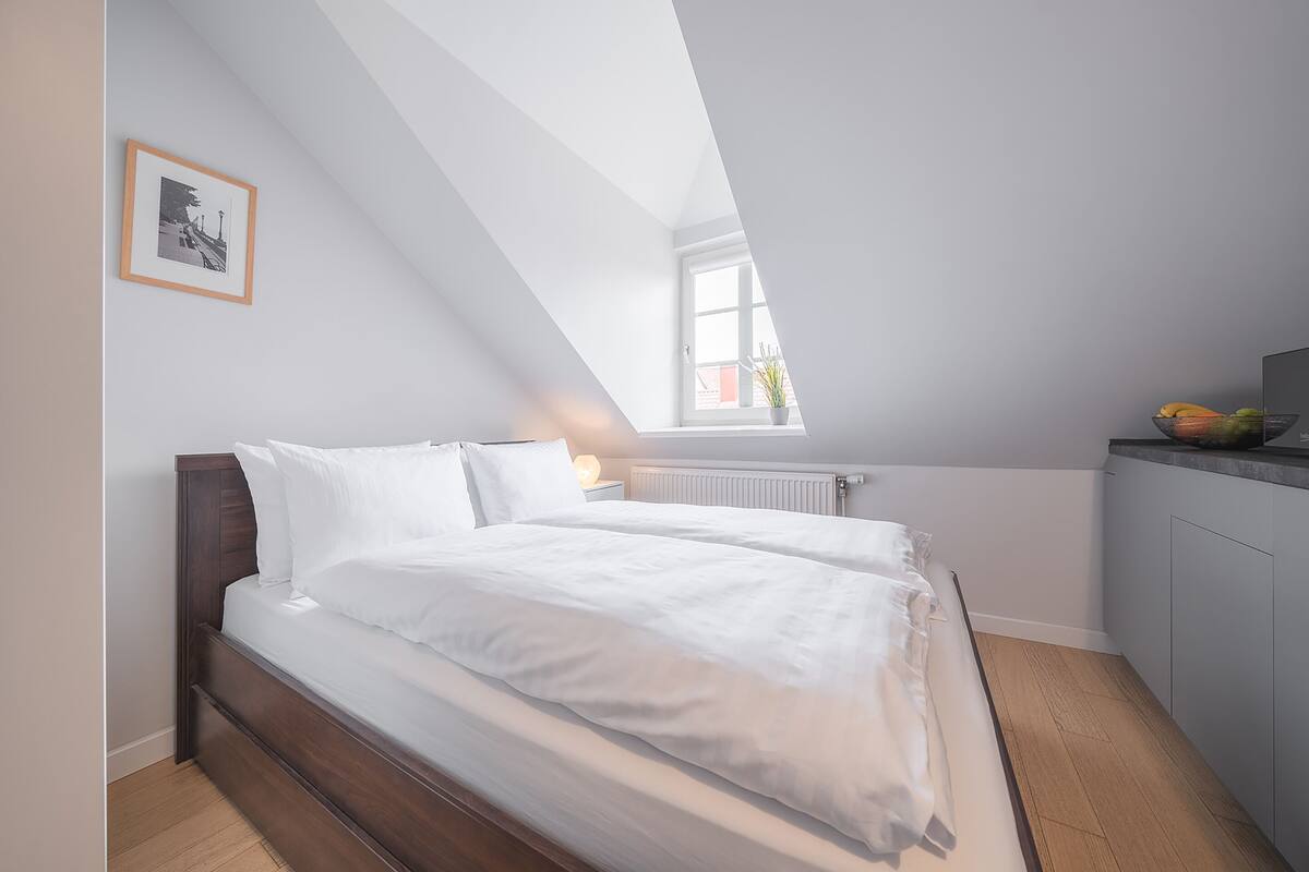 A bedroom with a bed, a window, and a view of the outside.