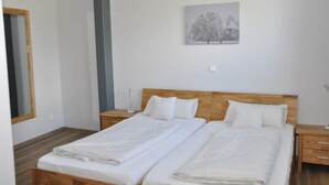 A double bed with white linens, a wooden headboard, a bedside table with a lamp, and a framed picture on the wall. - Steakhaus Büffel Ferienwohnung 3 70qm (Heimbach)