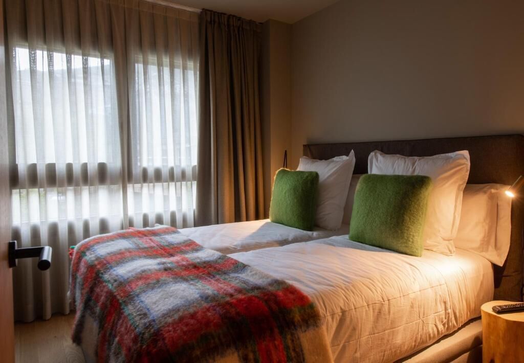 Una camera d'albergo con un letto grande, una finestra con tende e un comodino.